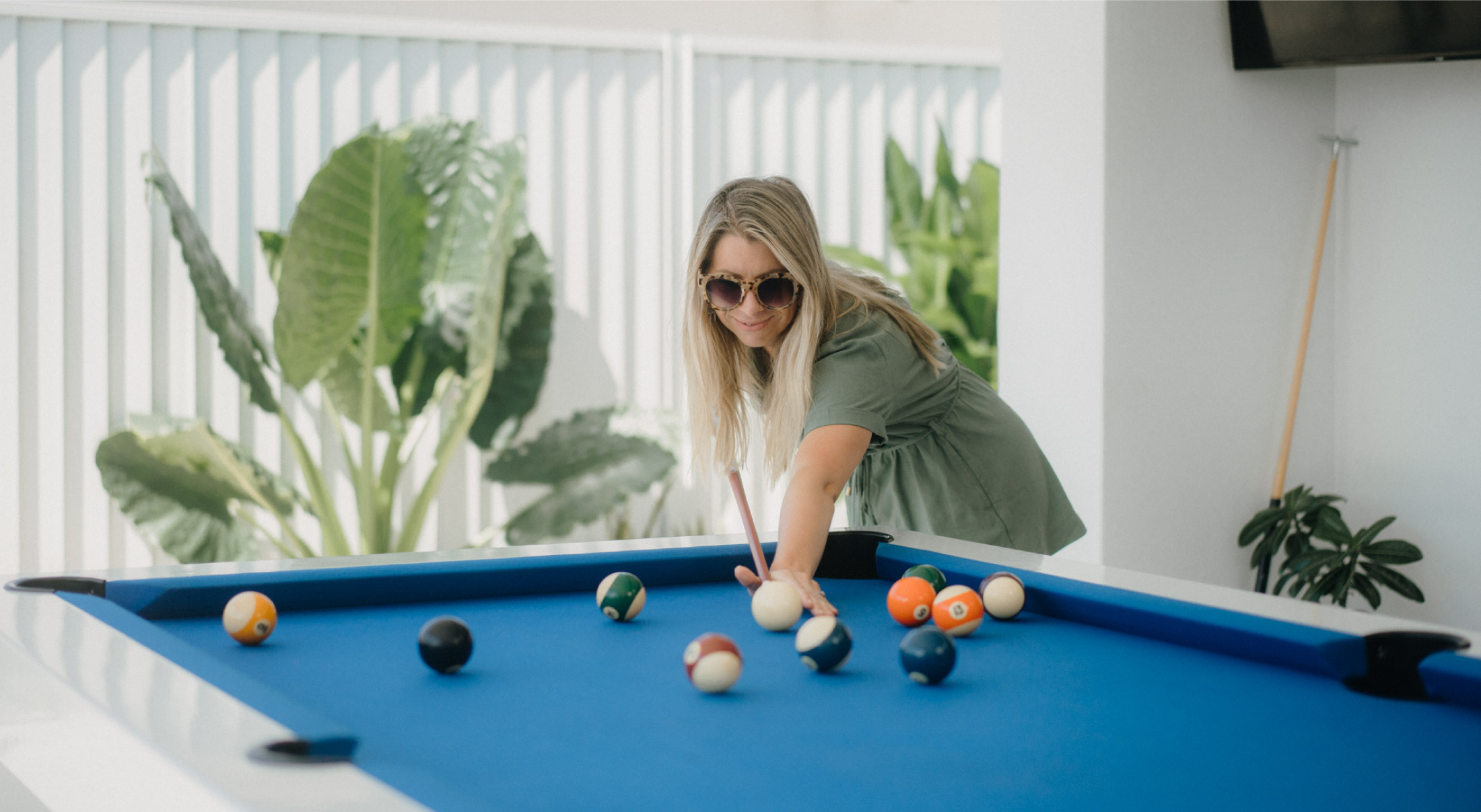 Woman playing pool on a white outdoor pool table with blue cloth